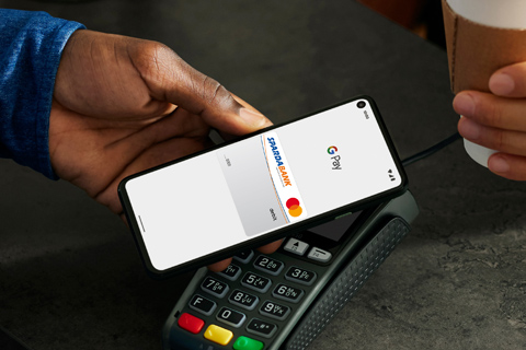 Ein Mann zahlt mit Google Pay am Smartphone im Café.